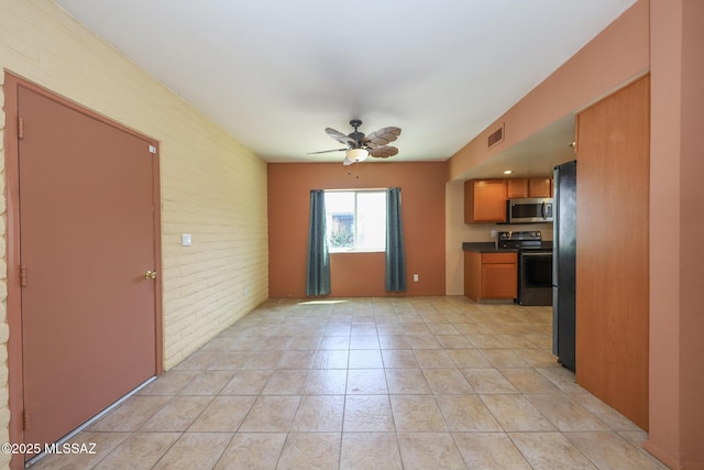 1641 S San Carla, Green Valley, AZ 85614 - kitchen with stainless steel microwave, range with electric cooktop, ceiling fan, freestanding refrigerator, and brick wall