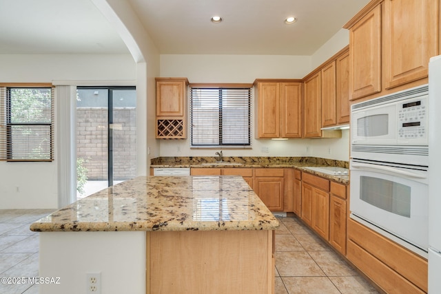 139 E Castlefield Cir, Tucson, AZ 85704 - kitchen featuring white appliances, a kitchen island, light tile patterned flooring, arched walkways, and light stone counters