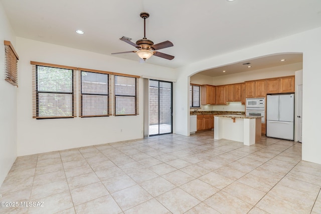 139 E Castlefield Cir, Tucson, AZ 85704 - kitchen featuring white appliances, ceiling fan, arched walkways, a breakfast bar area, and open floor plan
