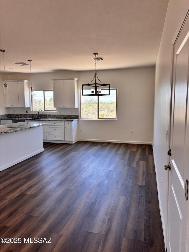 3152 E Andrada Rd, Vail, AZ 85641 - kitchen with dark wood finished floors, light stone counters, hanging light fixtures, a chandelier, and white cabinetry