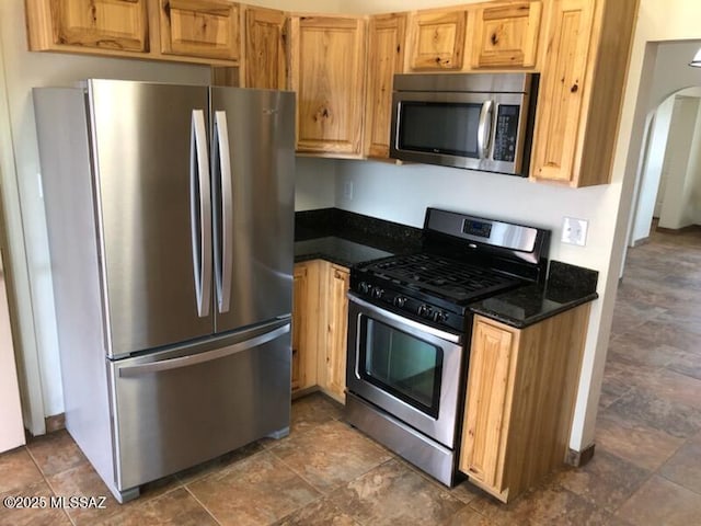 1048 E 7th St, Tucson, AZ 85719 - kitchen with appliances with stainless steel finishes, arched walkways, and dark stone countertops