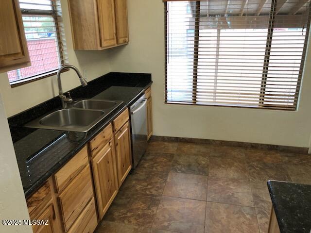 1048 E 7th St, Tucson, AZ 85719 - kitchen with stainless steel dishwasher, dark countertops, and brown cabinets