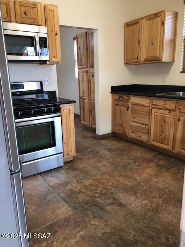 1048 E 7th St, Tucson, AZ 85719 - kitchen featuring stainless steel appliances, dark countertops, and stone finish floors