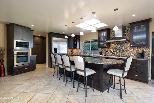 8142 N Modena Dr, Tucson, AZ 85742 - kitchen featuring built in appliances, wall chimney exhaust hood, backsplash, light tile patterned flooring, and recessed lighting