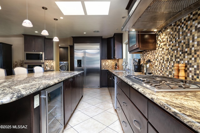8142 N Modena Dr, Tucson, AZ 85742 - kitchen featuring built in appliances, wine cooler, exhaust hood, tasteful backsplash, and washer / dryer