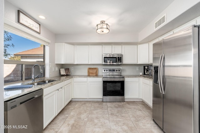 4660 E Torrey Pines Ln, Chandler, AZ 85249 - kitchen with appliances with stainless steel finishes, white cabinetry, light stone countertops, and light tile patterned floors