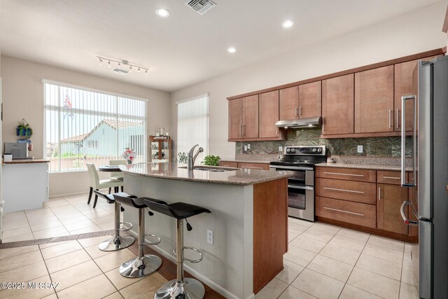 938 E Grass Meadow Pl, Oro Valley, AZ 85755 - kitchen with appliances with stainless steel finishes, under cabinet range hood, light tile patterned flooring, brown cabinetry, and recessed lighting