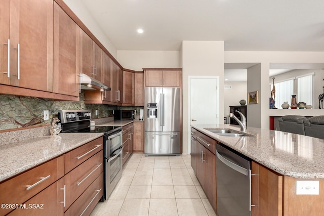 938 E Grass Meadow Pl, Oro Valley, AZ 85755 - kitchen featuring appliances with stainless steel finishes, under cabinet range hood, backsplash, light stone counters, and brown cabinets
