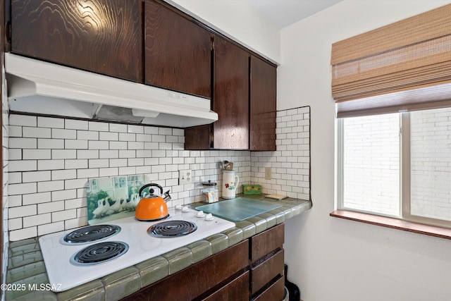 8450 E Old Spanish Trl Apt 154, Tucson, AZ 85710 - kitchen with tile counters, dark brown cabinets, tasteful backsplash, white electric cooktop, and under cabinet range hood