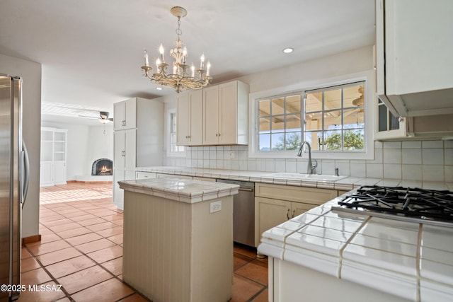 5015 N Via Condesa, Tucson, AZ 85718 - kitchen featuring stainless steel appliances, backsplash, tile countertops, a lit fireplace, and recessed lighting