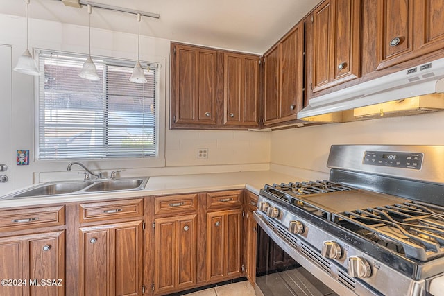 303 Paseo Madera Unit C, Green Valley, AZ 85614 - kitchen with stainless steel gas range, under cabinet range hood, brown cabinets, light countertops, and hanging light fixtures