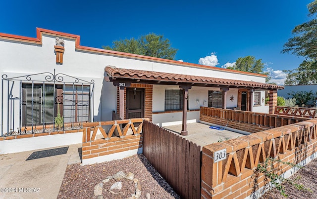 303 Paseo Madera Unit C, Green Valley, AZ 85614 - view of front of house featuring covered porch, stucco siding, a fenced front yard, and a tiled roof