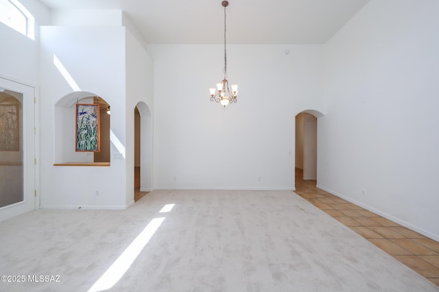 14085 E Copper Mesa Ct, Vail, AZ 85641 - tiled empty room featuring arched walkways, a chandelier, a towering ceiling, and carpet