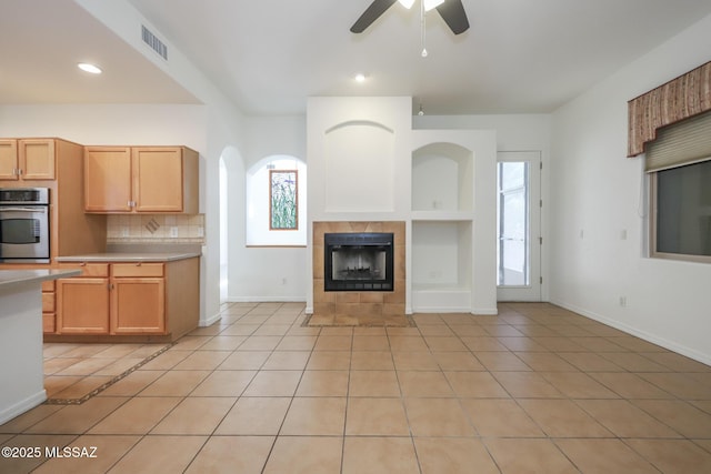 14085 E Copper Mesa Ct, Vail, AZ 85641 - kitchen featuring oven, light tile patterned flooring, ceiling fan, light countertops, and a tile fireplace
