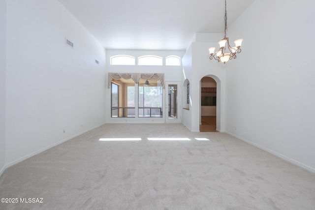 14085 E Copper Mesa Ct, Vail, AZ 85641 - unfurnished living room featuring arched walkways, carpet flooring, a chandelier, and a high ceiling