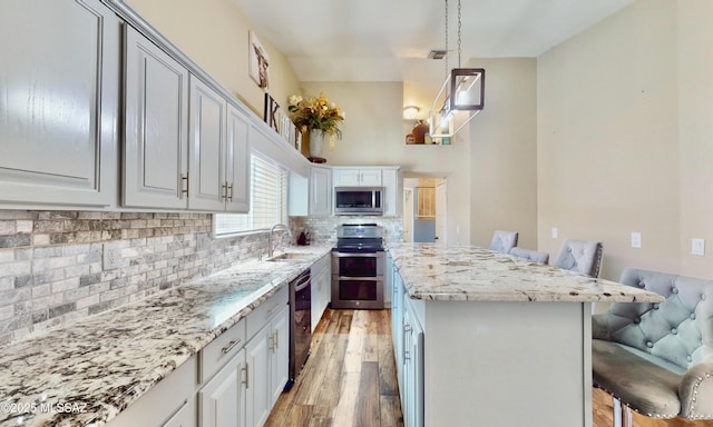 8942 N Ferber Ct, Tucson, AZ 85742 - kitchen with stainless steel appliances, light wood-style floors, a center island, a breakfast bar area, and backsplash
