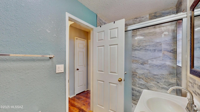 8942 N Ferber Ct, Tucson, AZ 85742 - bathroom featuring wood finished floors, a textured ceiling, a textured wall, and vanity