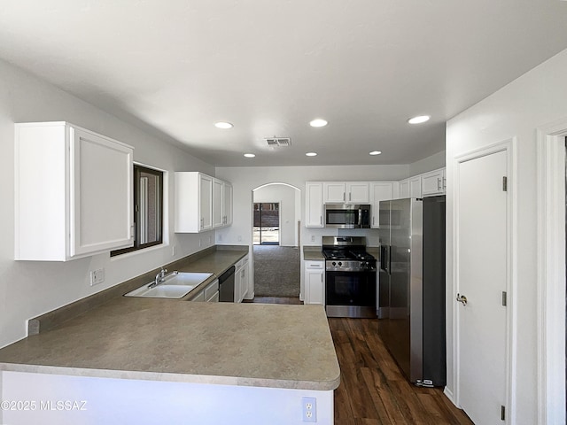 8758 E Mountain Spring Dr, Tucson, AZ 85747 - kitchen with stainless steel appliances, arched walkways, dark wood-style floors, white cabinets, and a peninsula