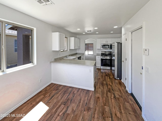8758 E Mountain Spring Dr, Tucson, AZ 85747 - kitchen with appliances with stainless steel finishes, dark wood finished floors, a peninsula, recessed lighting, and white cabinetry