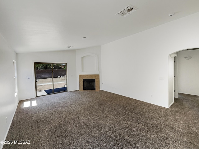 8758 E Mountain Spring Dr, Tucson, AZ 85747 - unfurnished living room featuring carpet, arched walkways, and a tiled fireplace
