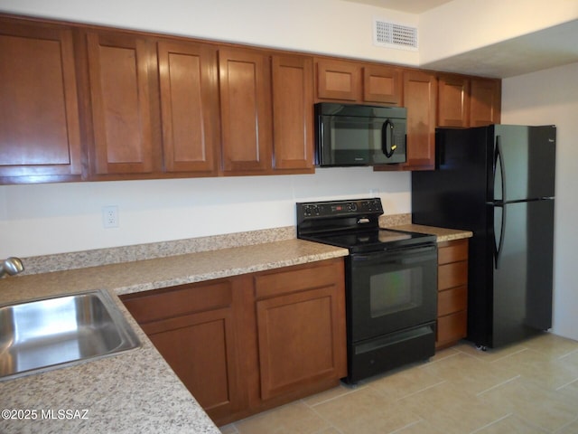 1809 E Miles St, Tucson, AZ 85719 - kitchen with black appliances, brown cabinets, light countertops, and light tile patterned floors