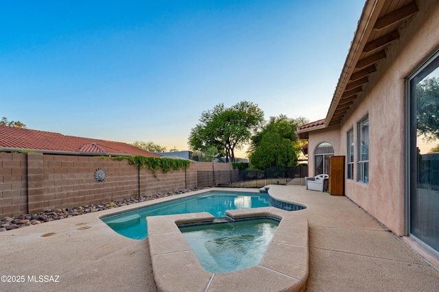 11120 E Mountain Gate Pl, Tucson, AZ 85749 - pool at dusk featuring a fenced backyard, a patio, and a pool with connected hot tub