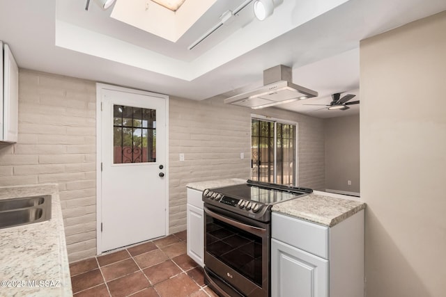 7208 E Toronto St, Tucson, AZ 85730 - kitchen featuring stainless steel electric stove, wall chimney exhaust hood, light countertops, ceiling fan, and white cabinetry