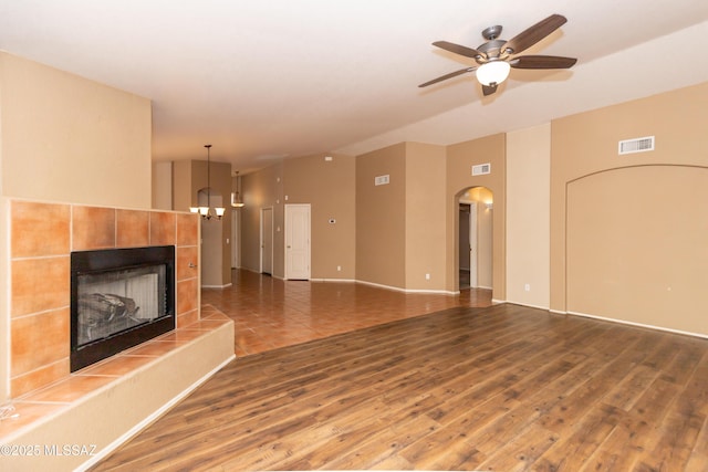5566 W Dove Of Peace Dr, Marana, AZ 85658 - unfurnished living room featuring a fireplace, arched walkways, wood finished floors, and ceiling fan