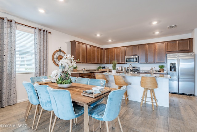 10490 W Beaman Ln, Marana, AZ 85653 - kitchen with stainless steel appliances, an island with sink, light wood-style floors, recessed lighting, and light stone counters