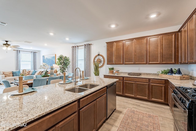 10490 W Beaman Ln, Marana, AZ 85653 - kitchen with stainless steel dishwasher, black gas range oven, light stone counters, light wood-type flooring, and a ceiling fan