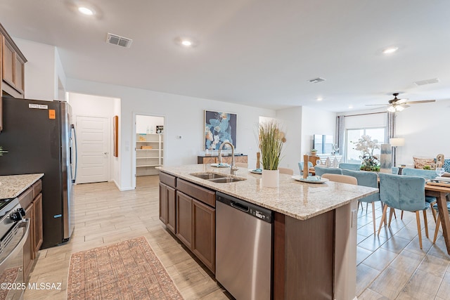 10490 W Beaman Ln, Marana, AZ 85653 - kitchen with appliances with stainless steel finishes, a ceiling fan, light wood-type flooring, an island with sink, and light stone countertops