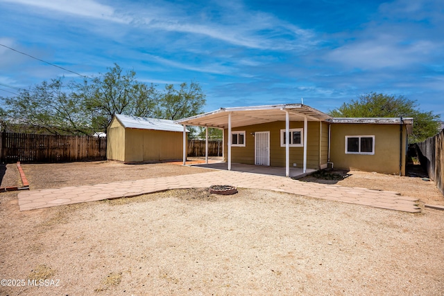 4812 E 3rd St, Tucson, AZ 85711 - rear view of house featuring a patio area, a fire pit, a fenced backyard, and a storage unit