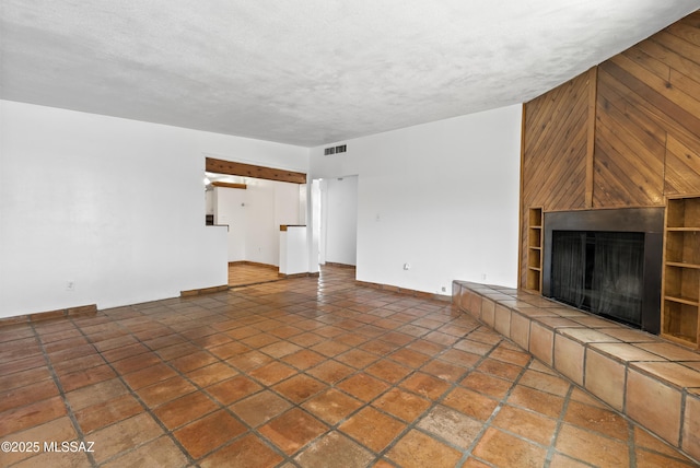 4812 E 3rd St, Tucson, AZ 85711 - unfurnished living room featuring a tile fireplace, wood walls, a textured ceiling, and tile patterned flooring