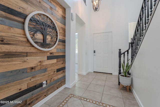 10567 E Desert Drifter Pl, Tucson, AZ 85747 - foyer entrance featuring wooden walls, stairs, light tile patterned floors, a towering ceiling, and a chandelier