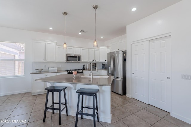 10567 E Desert Drifter Pl, Tucson, AZ 85747 - kitchen with appliances with stainless steel finishes, light tile patterned floors, a kitchen breakfast bar, white cabinets, and a center island with sink