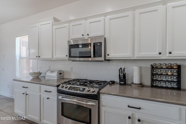 10567 E Desert Drifter Pl, Tucson, AZ 85747 - kitchen featuring stainless steel appliances, white cabinetry, decorative backsplash, light tile patterned floors, and dark stone countertops