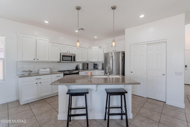 10567 E Desert Drifter Pl, Tucson, AZ 85747 - kitchen with stainless steel appliances, a kitchen bar, white cabinets, light tile patterned floors, and recessed lighting