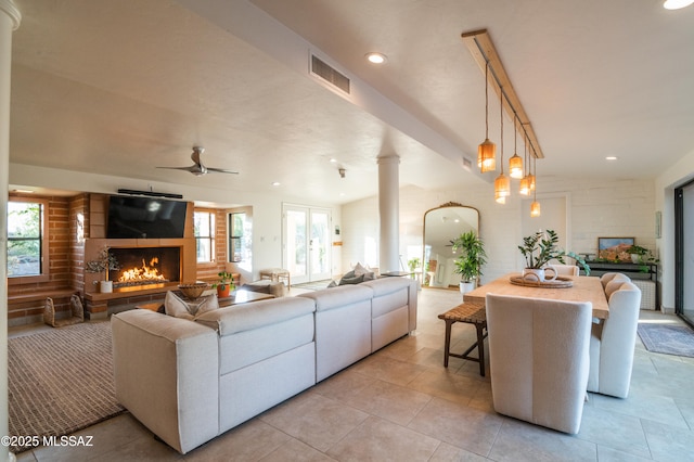 1115 W Santo Domingo Cir, Tucson, AZ 85704 - living room with a warm lit fireplace, ceiling fan, light tile patterned floors, and decorative columns
