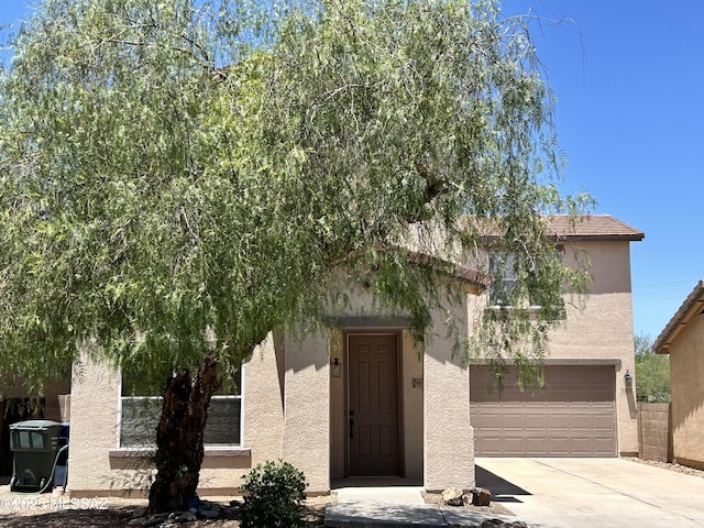 3365 N River Rapids Dr, Tucson, AZ 85712 - view of property hidden behind natural elements with an attached garage, driveway, and stucco siding