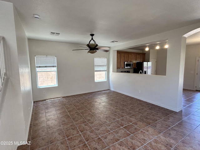 3365 N River Rapids Dr, Tucson, AZ 85712 - unfurnished living room with arched walkways, a ceiling fan, and dark tile patterned flooring