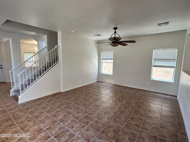 3365 N River Rapids Dr, Tucson, AZ 85712 - spare room with a ceiling fan, arched walkways, dark tile patterned flooring, and stairs