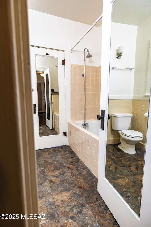 1809 E 8th St, Tucson, AZ 85719 - bathroom with tiled shower / bath combo, tile walls, a wainscoted wall, and stone finish floors