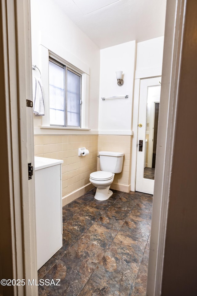 1809 E 8th St, Tucson, AZ 85719 - bathroom featuring tile walls, vanity, stone finish flooring, and wainscoting