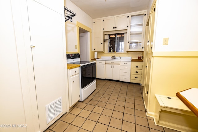 1809 E 8th St, Tucson, AZ 85719 - kitchen with range with electric stovetop, light tile patterned flooring, white cabinetry, light countertops, and glass insert cabinets