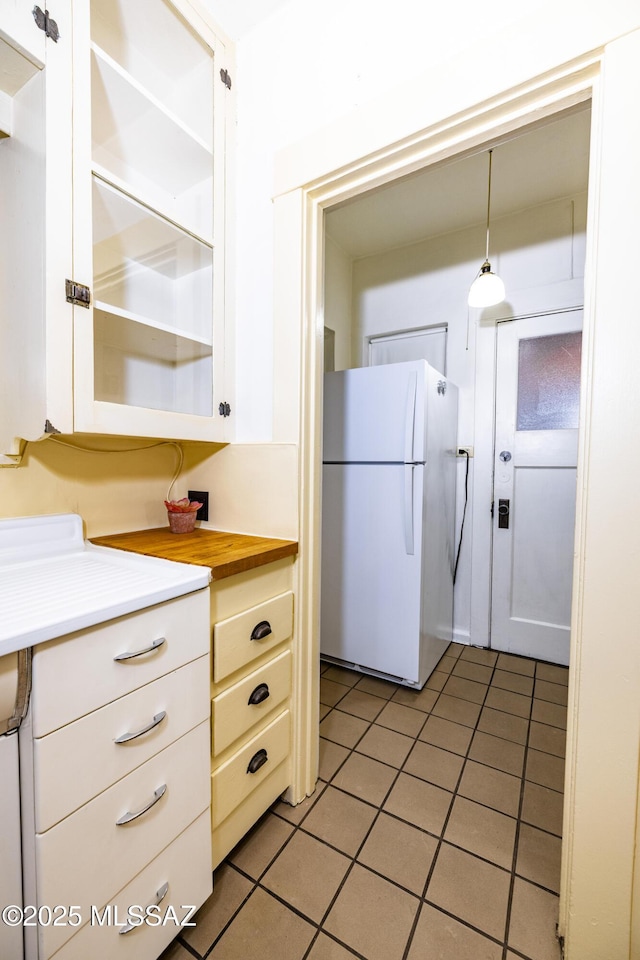 1809 E 8th St, Tucson, AZ 85719 - kitchen with freestanding refrigerator, light tile patterned floors, open shelves, white cabinetry, and hanging light fixtures