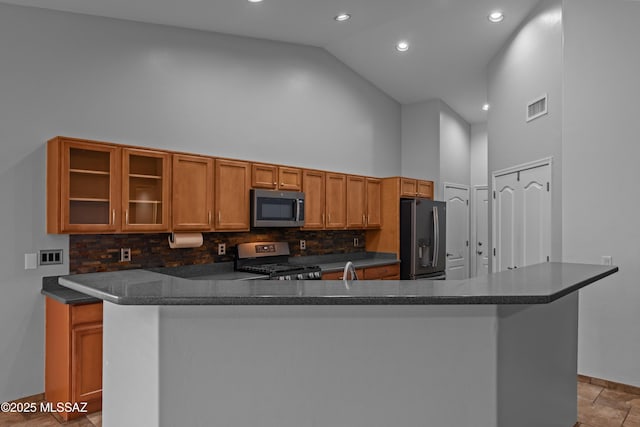 1026 E Madera Estates Ln, Sahuarita, AZ 85629 - kitchen featuring stainless steel appliances, high vaulted ceiling, dark countertops, decorative backsplash, and brown cabinetry