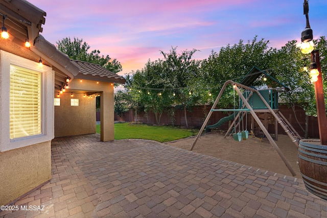 1026 E Madera Estates Ln, Sahuarita, AZ 85629 - patio terrace at dusk with a playground, a fenced backyard, and a patio area