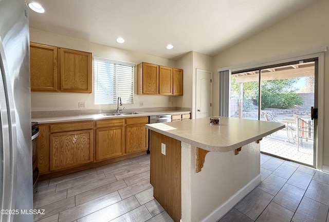 2898 W Simplicity Dr, Tucson, AZ 85741 - kitchen featuring appliances with stainless steel finishes, light countertops, a kitchen island, wood tiled floors, and a breakfast bar