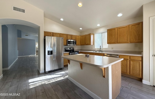 2898 W Simplicity Dr, Tucson, AZ 85741 - kitchen featuring stainless steel appliances, wood finish floors, a kitchen island, light countertops, and vaulted ceiling