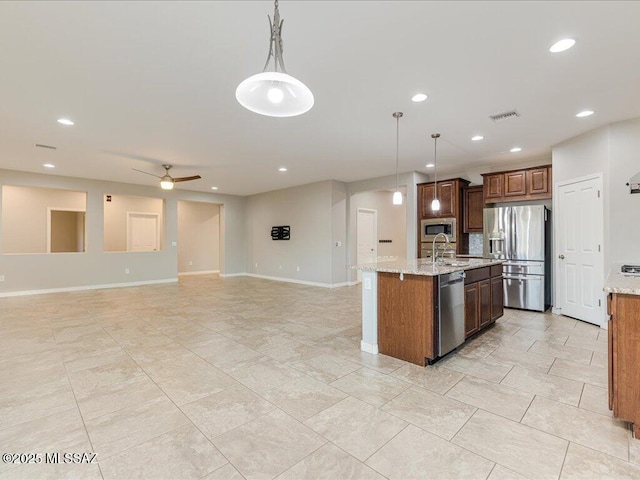 3872 W Sonoma Ranch Pl, Marana, AZ 85658 - kitchen with appliances with stainless steel finishes, a center island with sink, recessed lighting, hanging light fixtures, and light stone counters